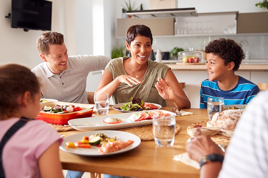 About Our Agency - Family Talking and Eating Meal Around Table At Home Together