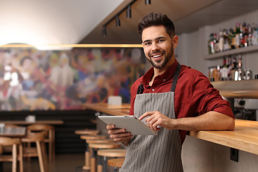 Business Insurance - Young Male Business Owner With Tablet Near Counter in His Cafe