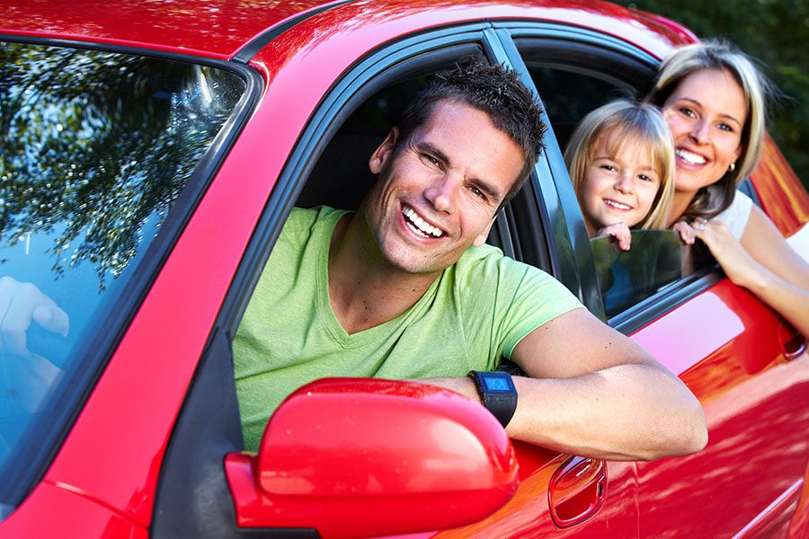 Personal Insurance - Family Smiling and Taking a Ride in Their Red Car Enjoying the Day